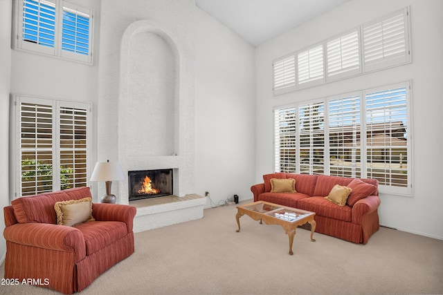 living room with a towering ceiling, carpet floors, a fireplace, and plenty of natural light