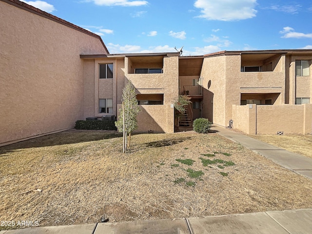 view of building exterior featuring fence and stairway