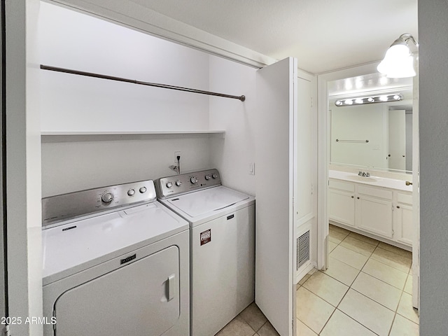 laundry room featuring washer and clothes dryer, light tile patterned floors, visible vents, a sink, and laundry area