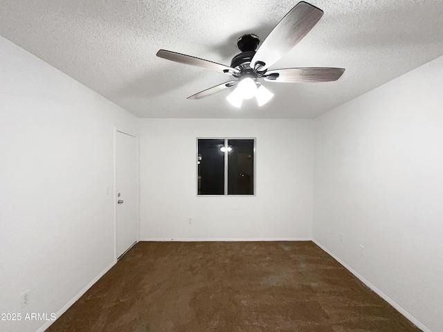 empty room featuring a textured ceiling, baseboards, dark colored carpet, and a ceiling fan