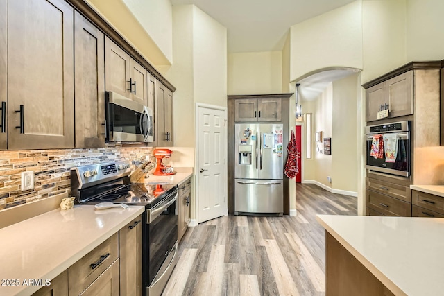 kitchen with backsplash, light hardwood / wood-style flooring, and stainless steel appliances