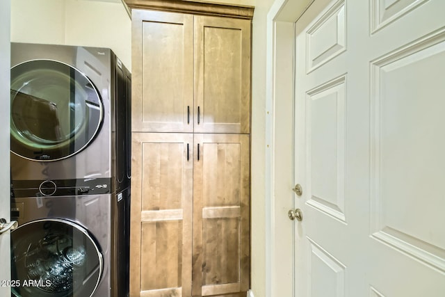 washroom with cabinets and stacked washer / dryer