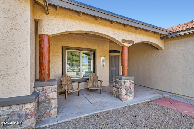 view of exterior entry with a patio