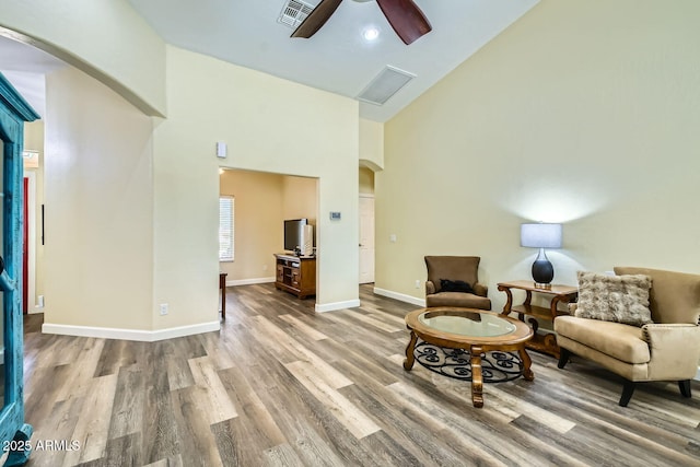 living area featuring hardwood / wood-style floors, high vaulted ceiling, and ceiling fan