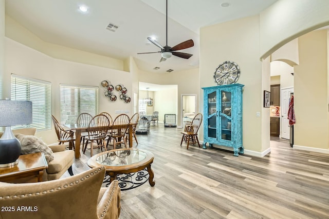 living room featuring light hardwood / wood-style flooring, ceiling fan, and a high ceiling