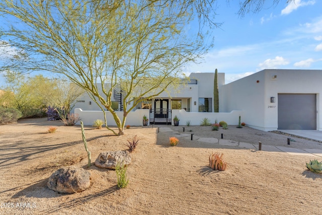 pueblo revival-style home featuring fence, a garage, and stucco siding