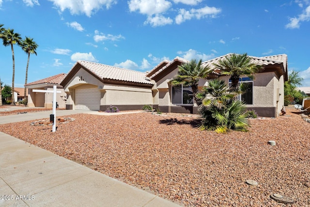 ranch-style home featuring a tiled roof, a garage, concrete driveway, and stucco siding