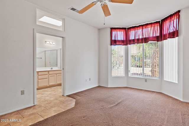spare room featuring visible vents, ceiling fan, light colored carpet, a sink, and light tile patterned floors