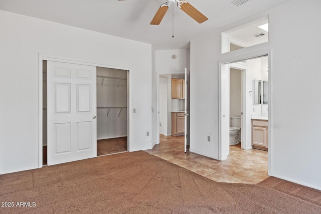 unfurnished bedroom with connected bathroom, light colored carpet, visible vents, and a closet