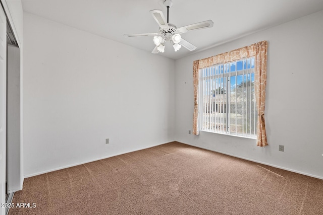 carpeted empty room featuring ceiling fan and baseboards