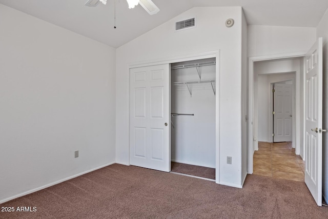 unfurnished bedroom with visible vents, a closet, lofted ceiling, baseboards, and carpet