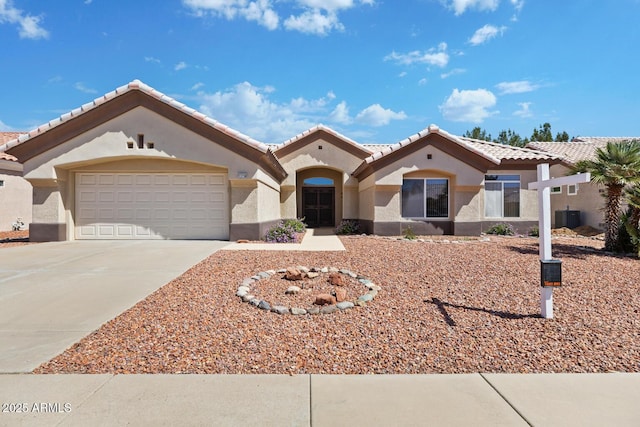 mediterranean / spanish-style home featuring a tiled roof, a garage, central air condition unit, concrete driveway, and stucco siding