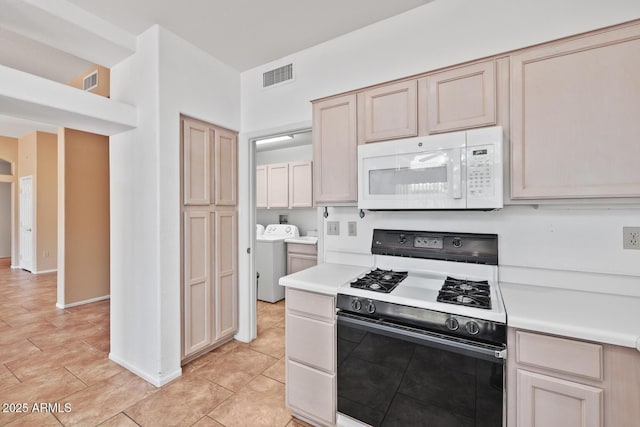 kitchen with visible vents, washing machine and dryer, light countertops, white microwave, and gas range oven