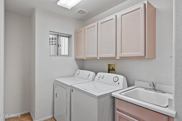 washroom with visible vents, a sink, cabinet space, and independent washer and dryer