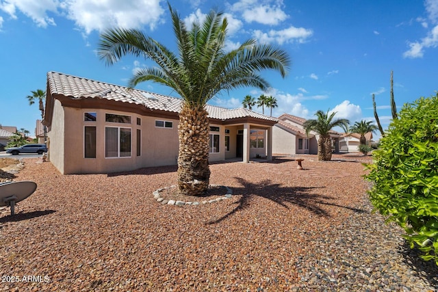 rear view of house featuring stucco siding and a tiled roof