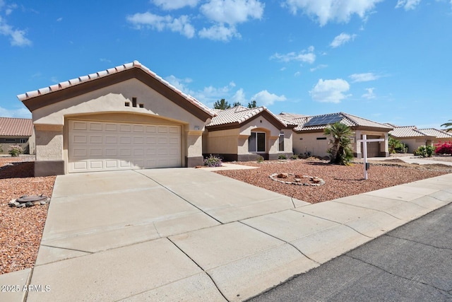 mediterranean / spanish home featuring a garage, stucco siding, solar panels, a tiled roof, and driveway