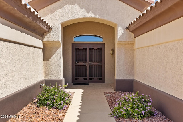 doorway to property featuring a tiled roof and stucco siding