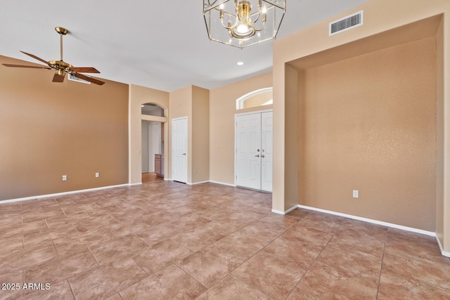 unfurnished room with visible vents, arched walkways, baseboards, and ceiling fan with notable chandelier