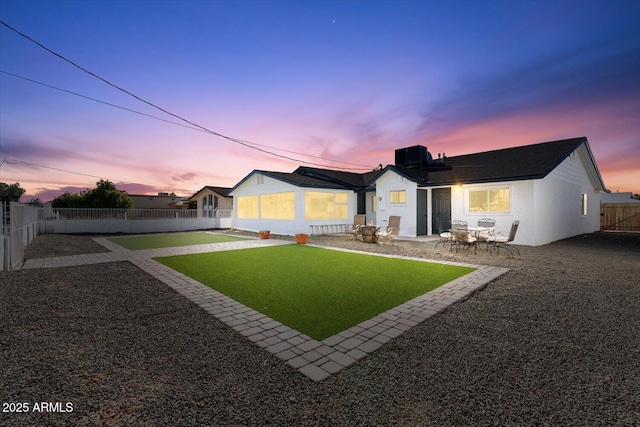 rear view of house featuring stucco siding, a fenced backyard, and a patio area