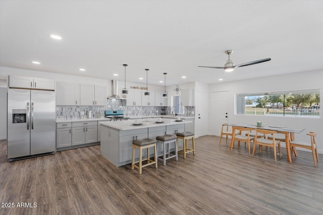 kitchen featuring tasteful backsplash, appliances with stainless steel finishes, light countertops, and wall chimney range hood