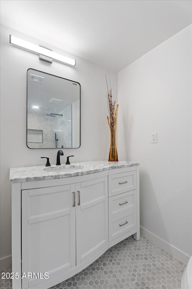 bathroom with vanity, baseboards, and a tile shower