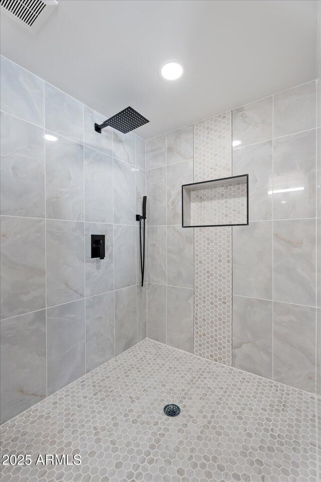 full bath featuring visible vents and a tile shower