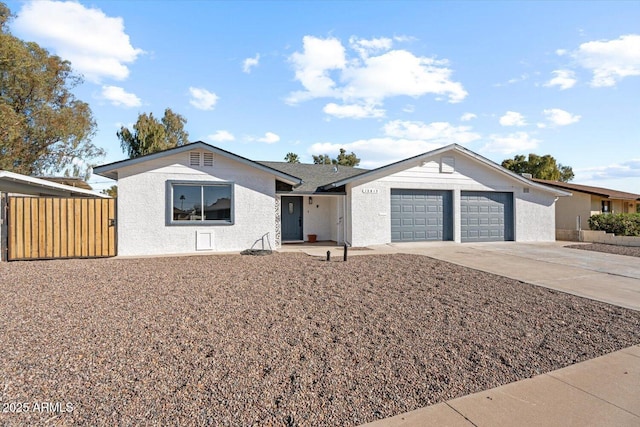 ranch-style home featuring an attached garage, fence, driveway, and stucco siding