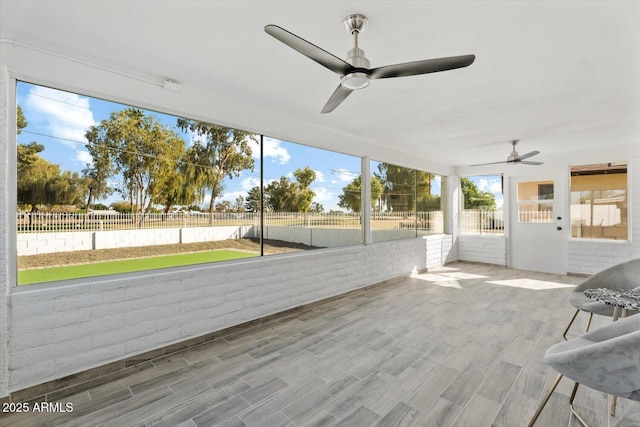 unfurnished sunroom with ceiling fan