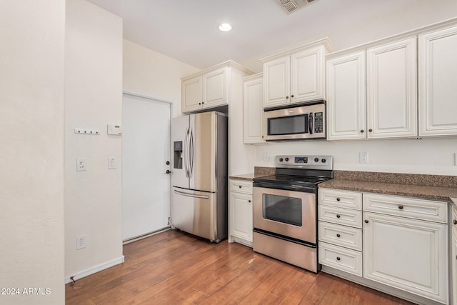 kitchen featuring hardwood / wood-style flooring, appliances with stainless steel finishes, and white cabinets