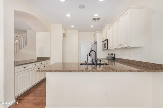 kitchen featuring kitchen peninsula, white cabinets, stainless steel appliances, and stone counters