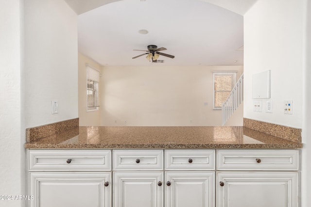 kitchen with ceiling fan, dark stone counters, and white cabinets