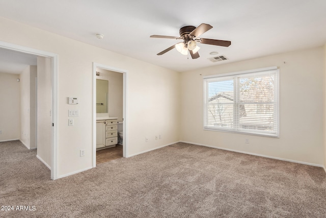 unfurnished bedroom featuring ensuite bathroom, light colored carpet, and ceiling fan