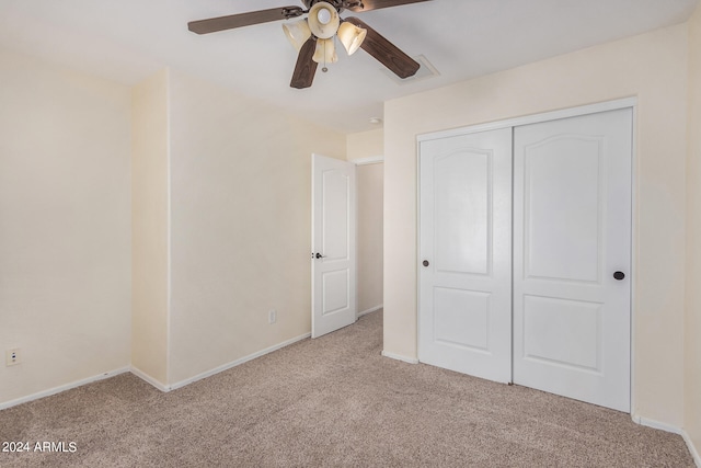 unfurnished bedroom featuring light carpet, a closet, and ceiling fan