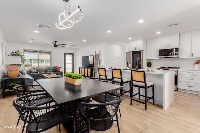 dining area featuring sink, light hardwood / wood-style floors, and ceiling fan