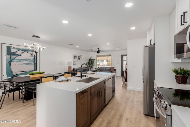 kitchen featuring sink, white cabinetry, hanging light fixtures, a center island with sink, and appliances with stainless steel finishes