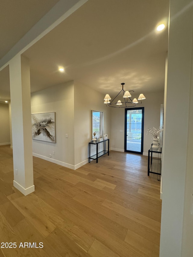 interior space featuring light wood-style floors, baseboards, and an inviting chandelier