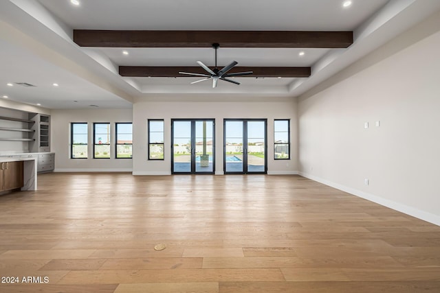 unfurnished living room featuring baseboards, ceiling fan, light wood-type flooring, and beam ceiling