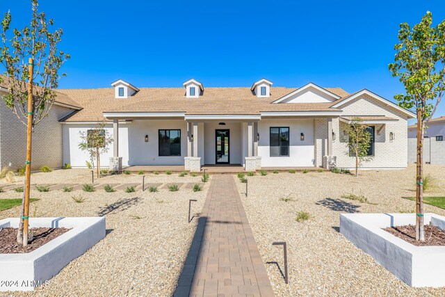 view of front of home featuring a porch, a shingled roof, stucco siding, and brick siding