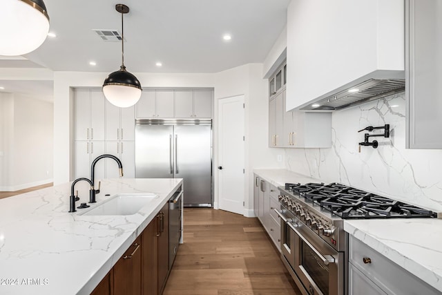 kitchen with a sink, recessed lighting, high end appliances, tasteful backsplash, and visible vents