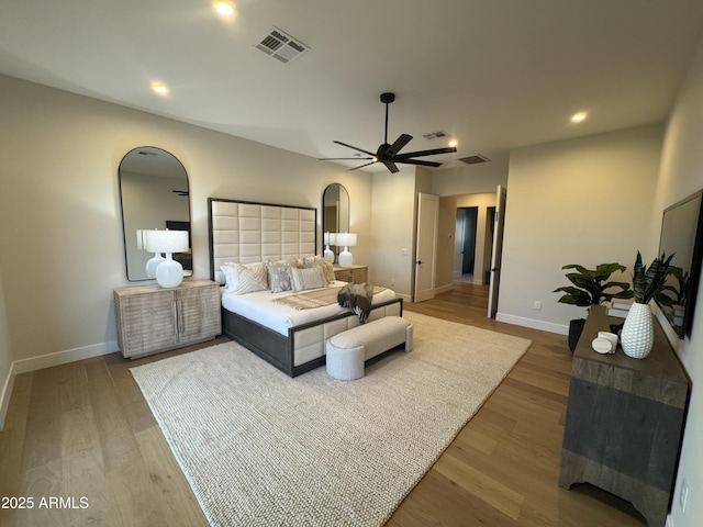 bedroom with arched walkways, baseboards, wood finished floors, and visible vents