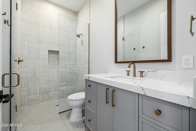 bathroom featuring toilet, an enclosed shower, vanity, and tile patterned flooring