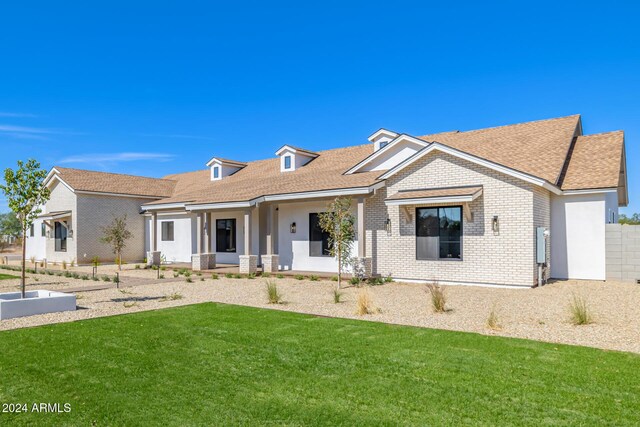 single story home with a shingled roof, a porch, brick siding, and a front yard
