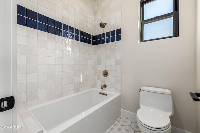 bathroom featuring tiled shower / bath combo, toilet, and tile patterned flooring