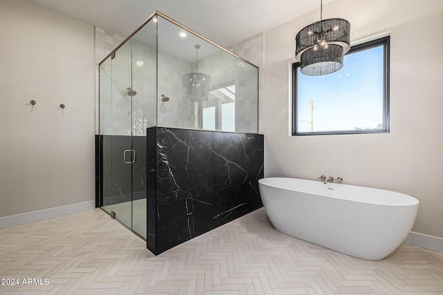 bathroom with a freestanding bath, baseboards, a shower stall, and a chandelier
