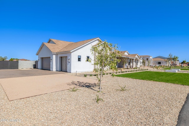 view of front facade featuring a residential view, an attached garage, a front lawn, stucco siding, and concrete driveway