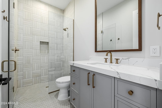 bathroom with vanity, toilet, and tiled shower