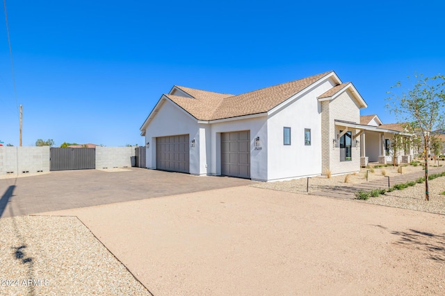 view of home's exterior featuring fence, stucco siding, a gate, an attached garage, and driveway