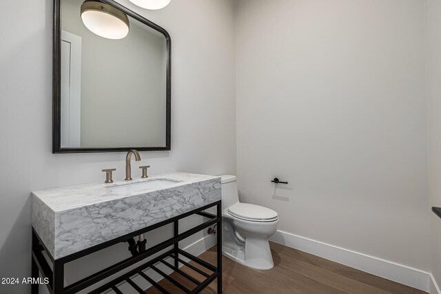 bathroom featuring baseboards, vanity, toilet, and wood finished floors