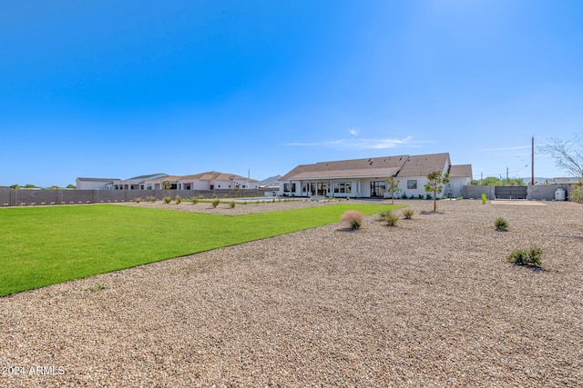 rear view of property featuring a lawn and fence