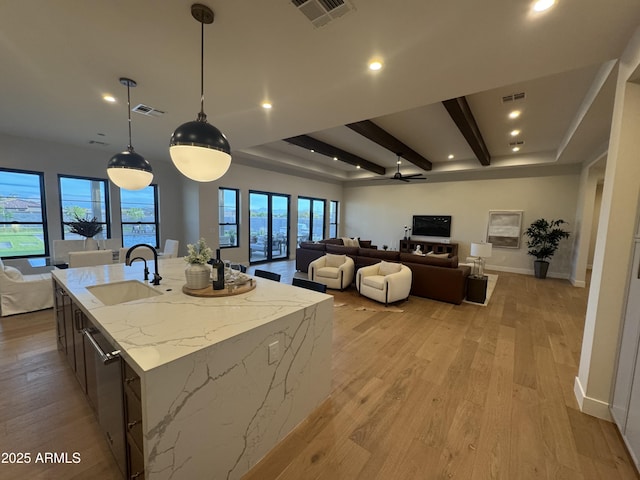 kitchen featuring a kitchen island with sink, open floor plan, visible vents, and a sink